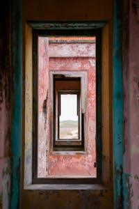 Rustic view through a series of colorful, weathered doorways in an abandoned building, Curaçao.