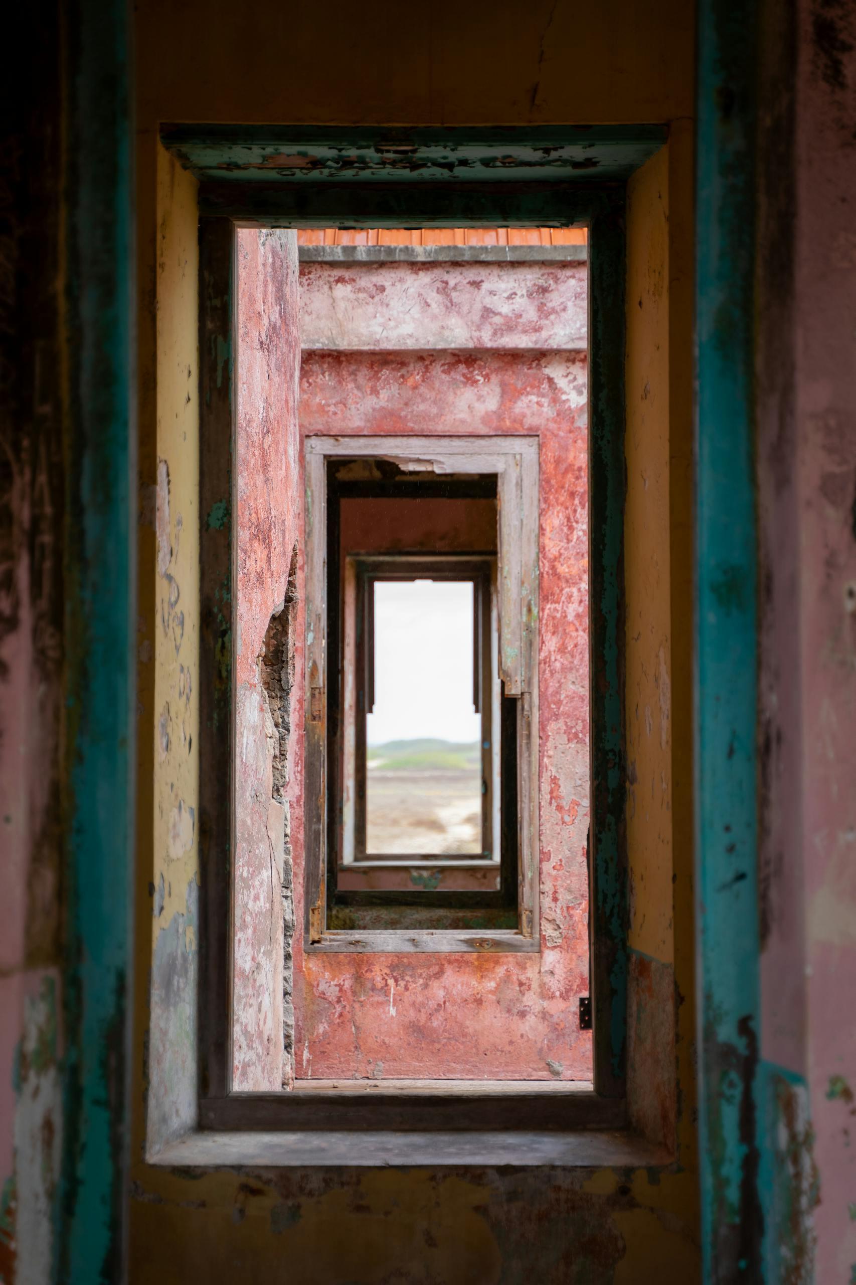 Rustic view through a series of colorful, weathered doorways in an abandoned building, Curaçao.