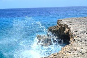 Vibrant ocean waves splashing against the rocky shoreline of Curaçao. A perfect tropical seascape for travel inspiration.